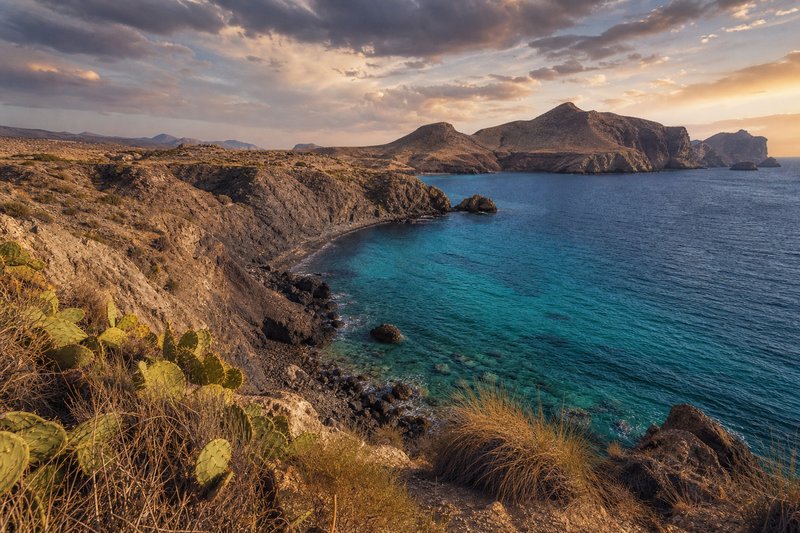 Cala del Parque Natural de Cabo de Gata-Níjar al atardecer, con aguas turquesa y costa volcánica